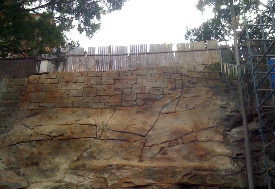 Patterned finish in the upper part of a retaining wall and mock rock in the lower part.